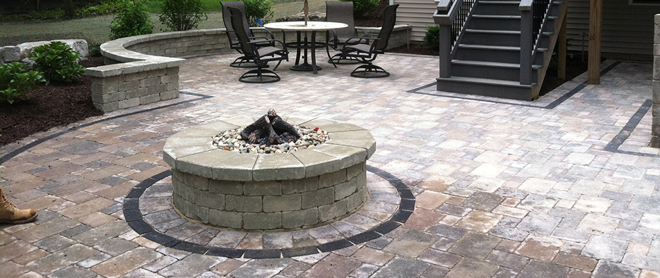 A fire pit installed near a seating wall over a patio in Lansing, MI.