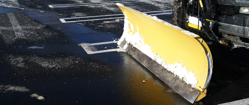 A yellow snow plow attached to our work truck for snow removal on a commercial property in Mason, MI. 